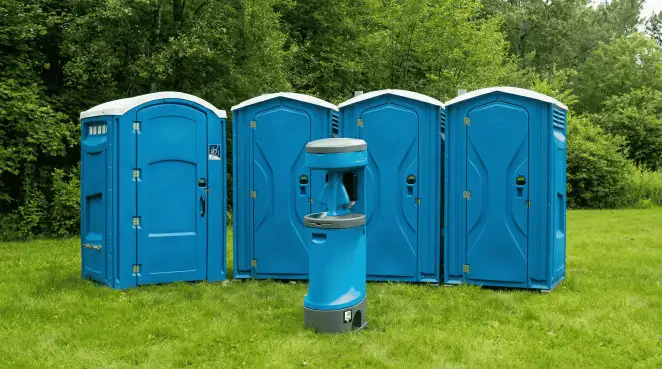 Four blue portable toilets and a matching hand washing station on grass near trees, a common sight at local outdoor events in Scottsdale, AZ