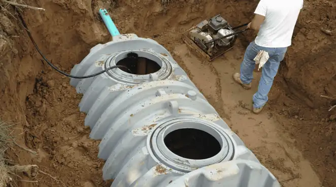 Septic tank installation showing a technician compacting soil around a new poly septic tank in an excavation pit in Scottsdale, AZ